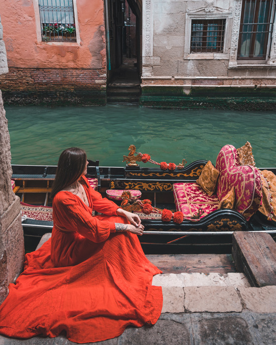 girl in a red dress sits next to a gondola