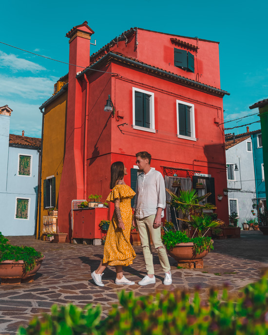 couple against the backdrop of an old red house in Murano